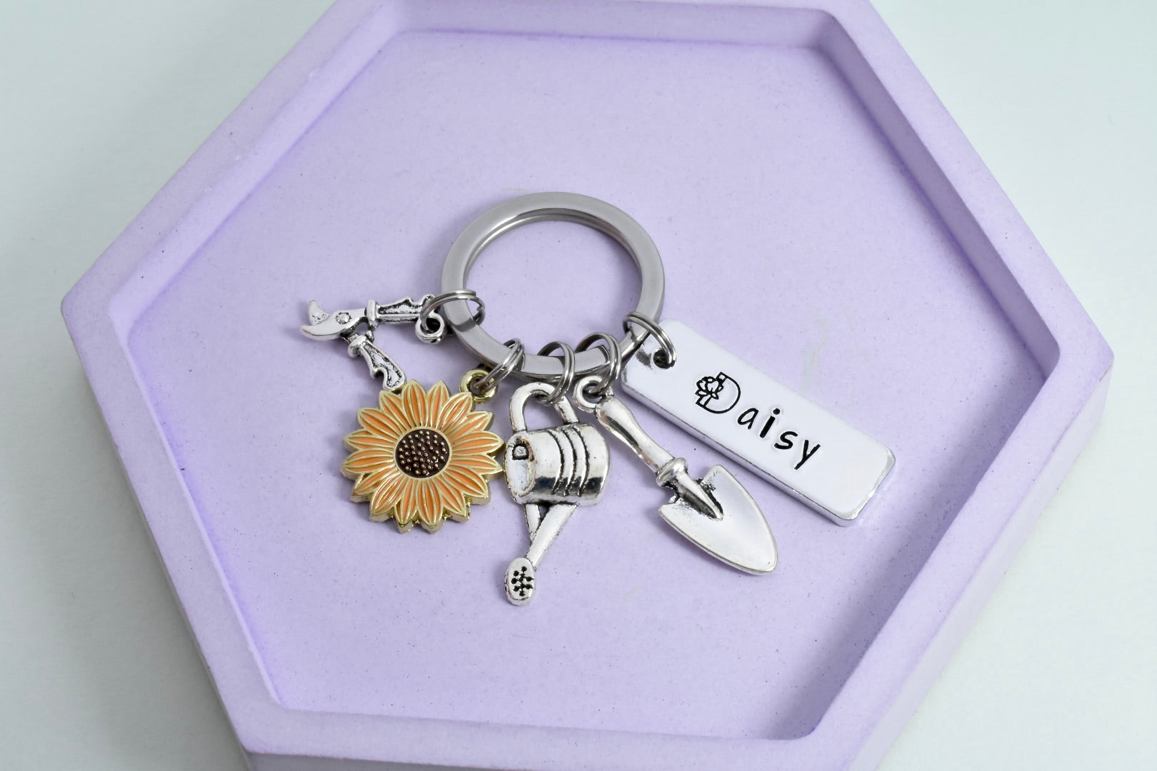A personalised gardeners keyring with a trowel, watering can, secateurs, and flower charms, with the recipient's name 'Daisy' printed on a tag.