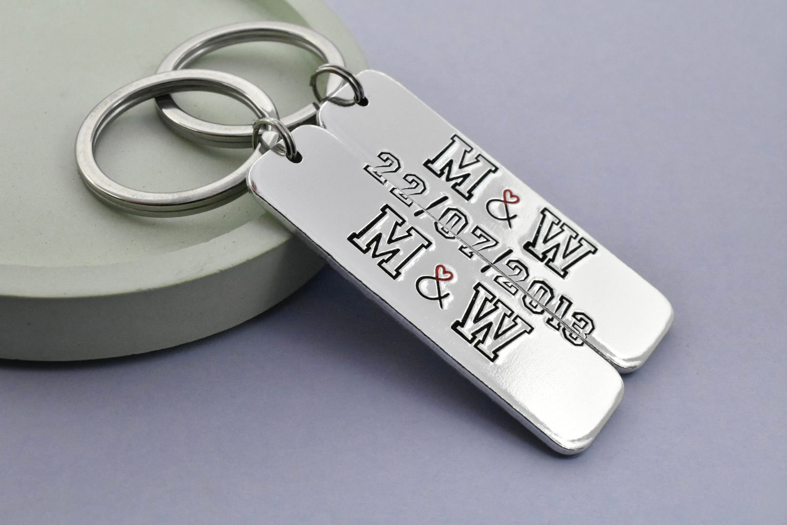 Silver keychain set of two with engraved initials and date on a gray background