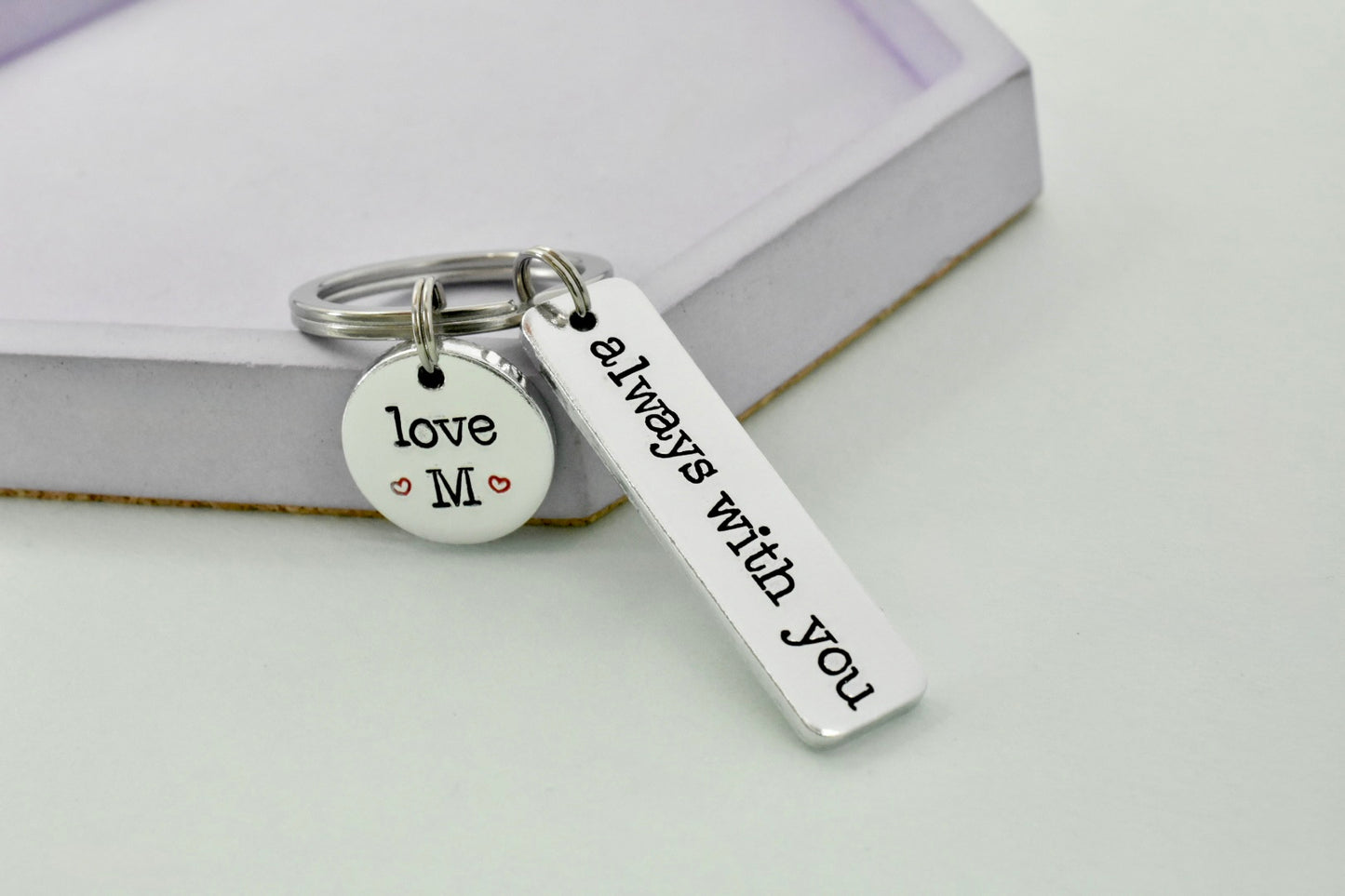 Silver keychain with 'love M' and 'always with you' tags on a light background