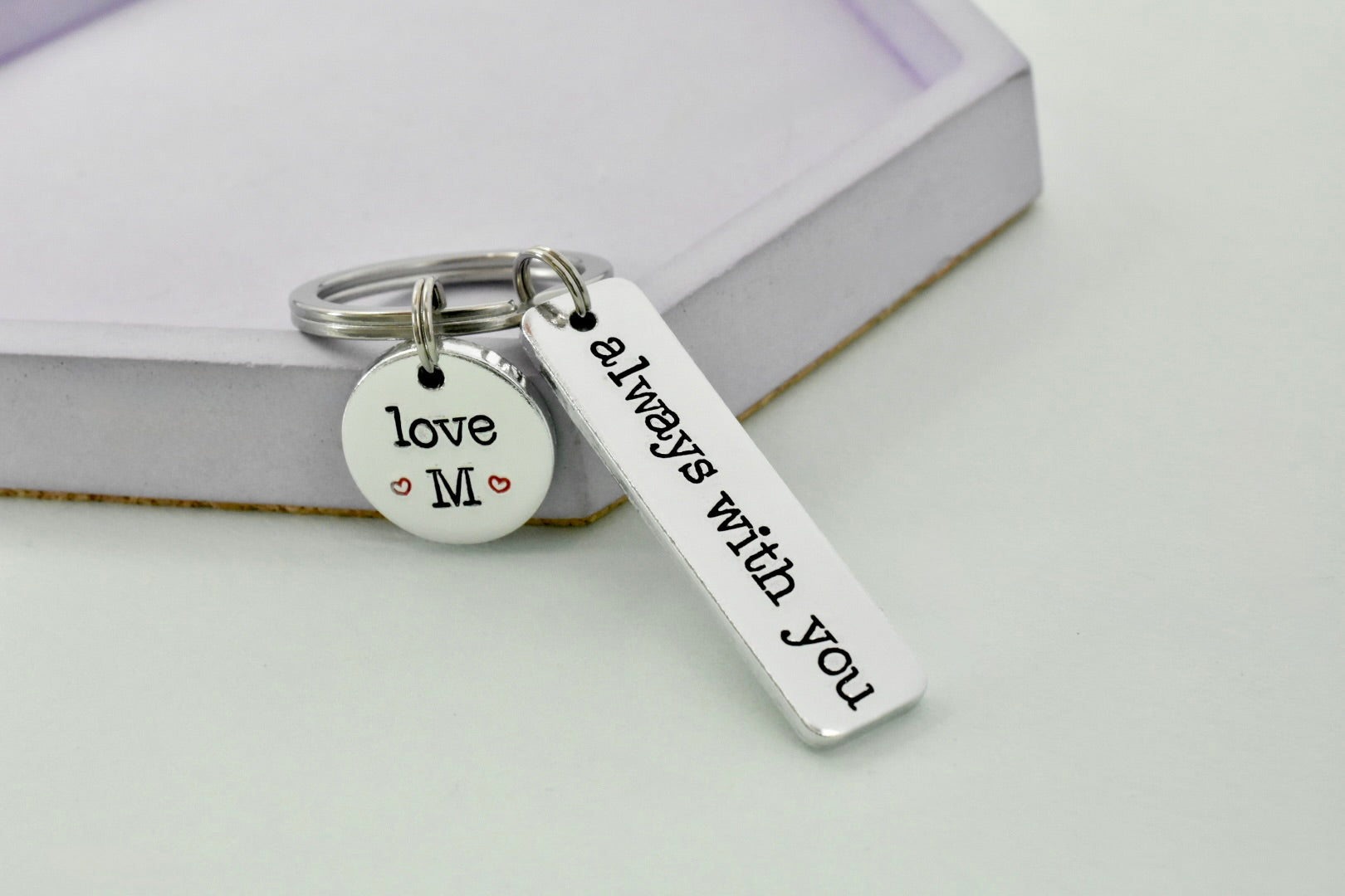 Silver keychain with 'love M' and 'always with you' tags on a light background