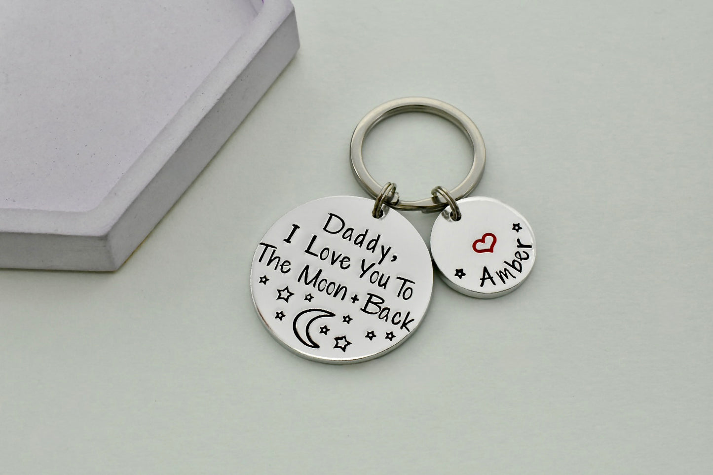 Keychain with love you to the moon and back message on two round tags against a light background