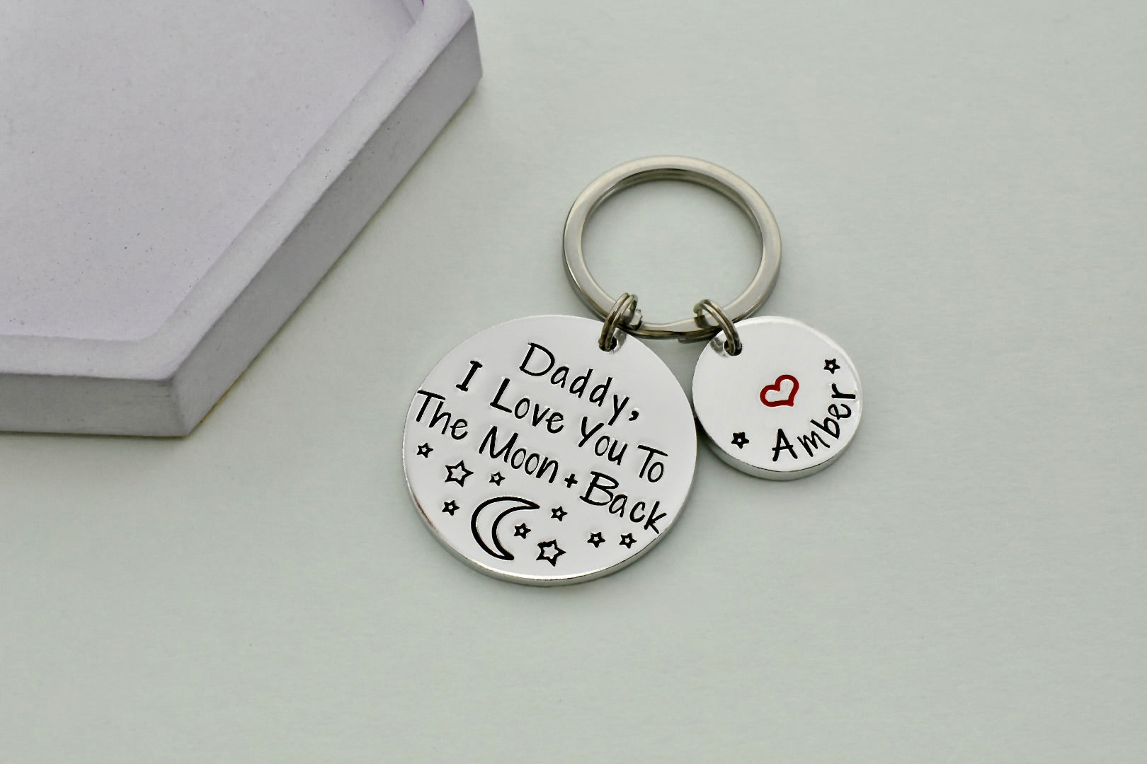 Keychain with love you to the moon and back message on two round tags against a light background
