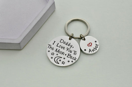 Keychain with love you to the moon and back message on two round tags against a light background