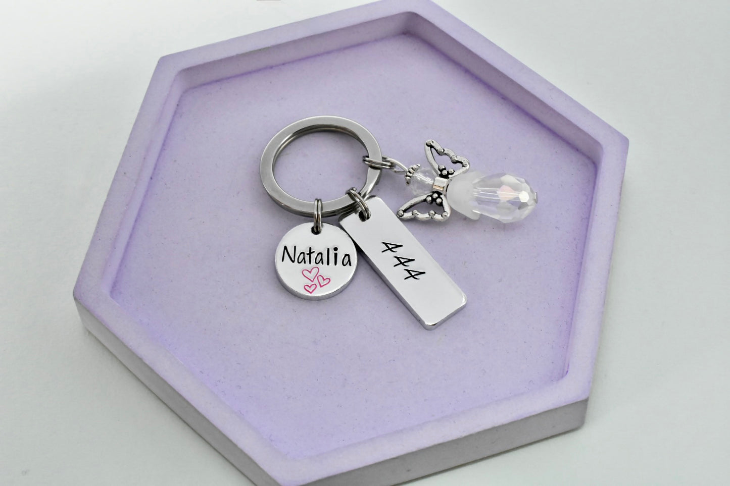 Keychain with personalised disc with name on and personaalised rectangle tag with angel numbers on, keychain also has a beaded angle charm on it.