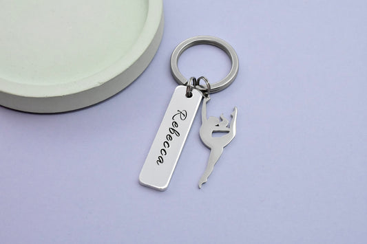 A personalised aluminium keyring with a gymnast silhouette charm and a split ring, engraved with a name.