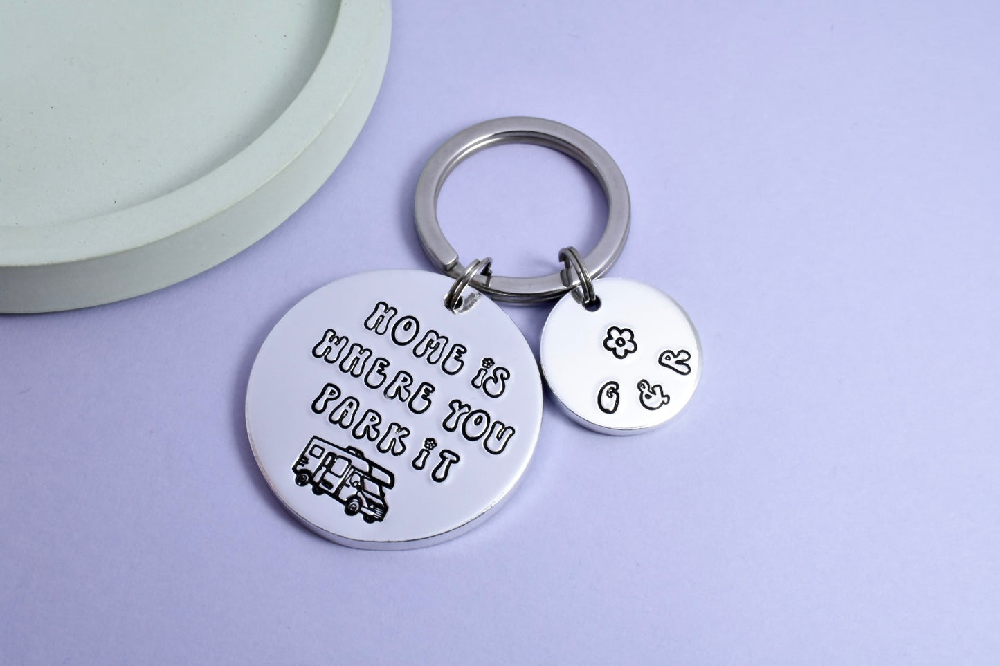 A keyring with a larger aluminium disc stamped with 'HOME IS WHERE YOU PARK IT' and a smaller aluminium disc with personalisation 