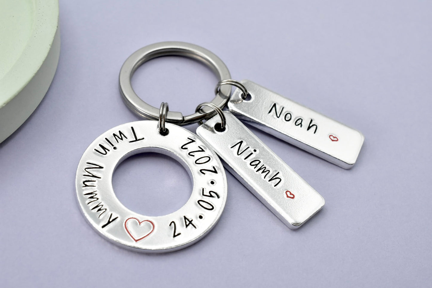 Personalised aluminum keyring with twin babies' names on silver rectangle tags, and silver washer shape with 'Twin Mummy' and twin's birthdate and big red heart design.