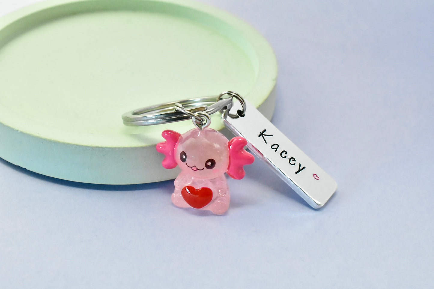 Keychain with a pink axolotl charm and a name tag on a light background
