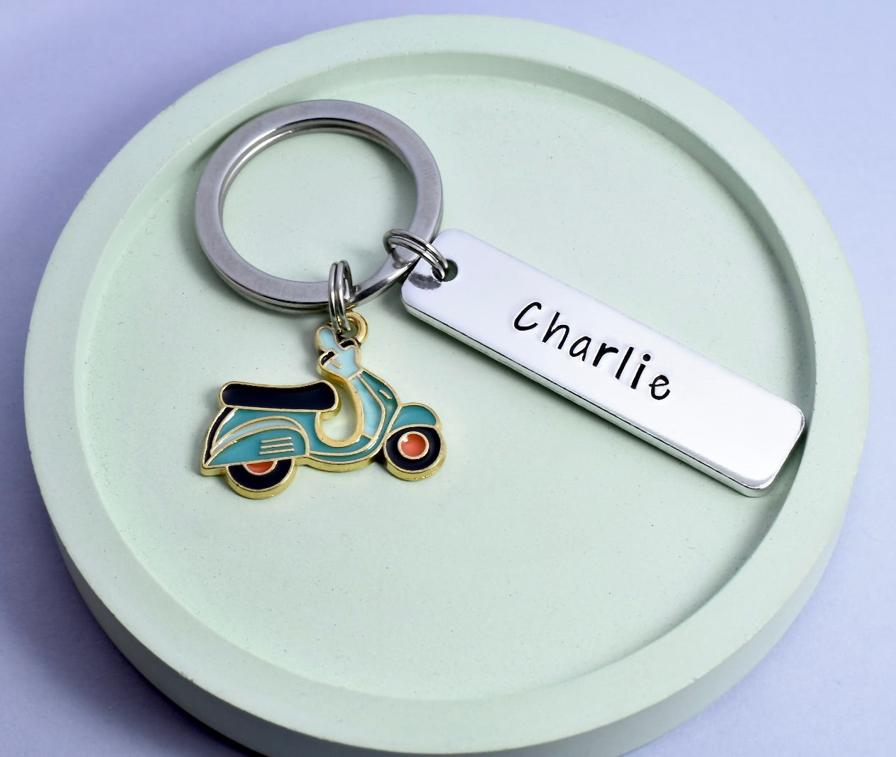 A personalised aluminium keyring with a moped charm and a split ring, engraved with the name 'Charlie' on a rectangular tag.
