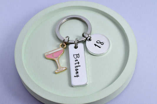 Personalised birthday keyring, name on silver rectangle tag, age 18 on silver disc charm and pink champagne cocktail charm