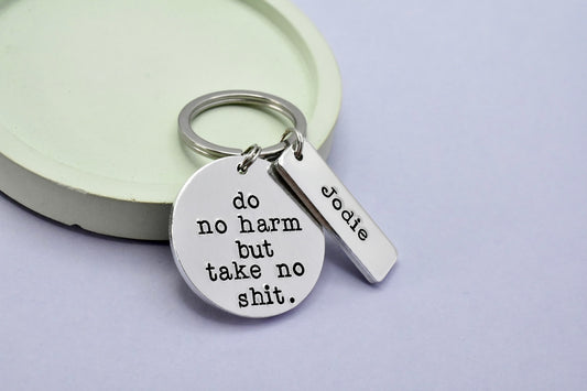 Keychain with 'do no harm but take no shit' tag and 'Jodie' name on a light purple background