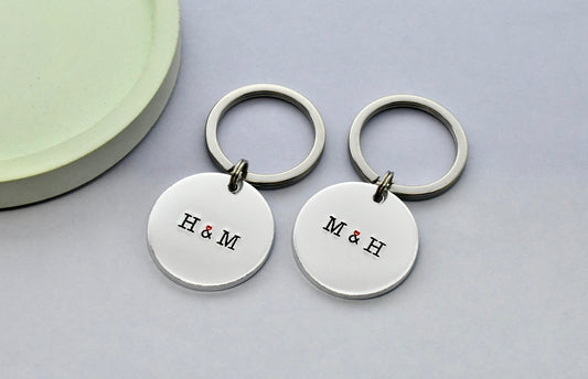 Two silver keychains with 'H&M' initials on a light gray background