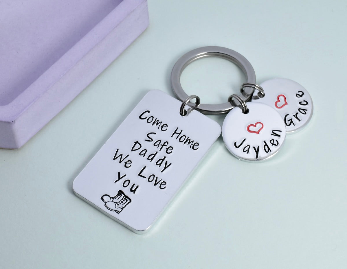 A personalised aluminium keyring with rectangular and small disc charms. The rectangular charm has the text 'Come Home Safe Daddy We Love You' and a heart symbol. Discs are personalised with children's names and red heart design