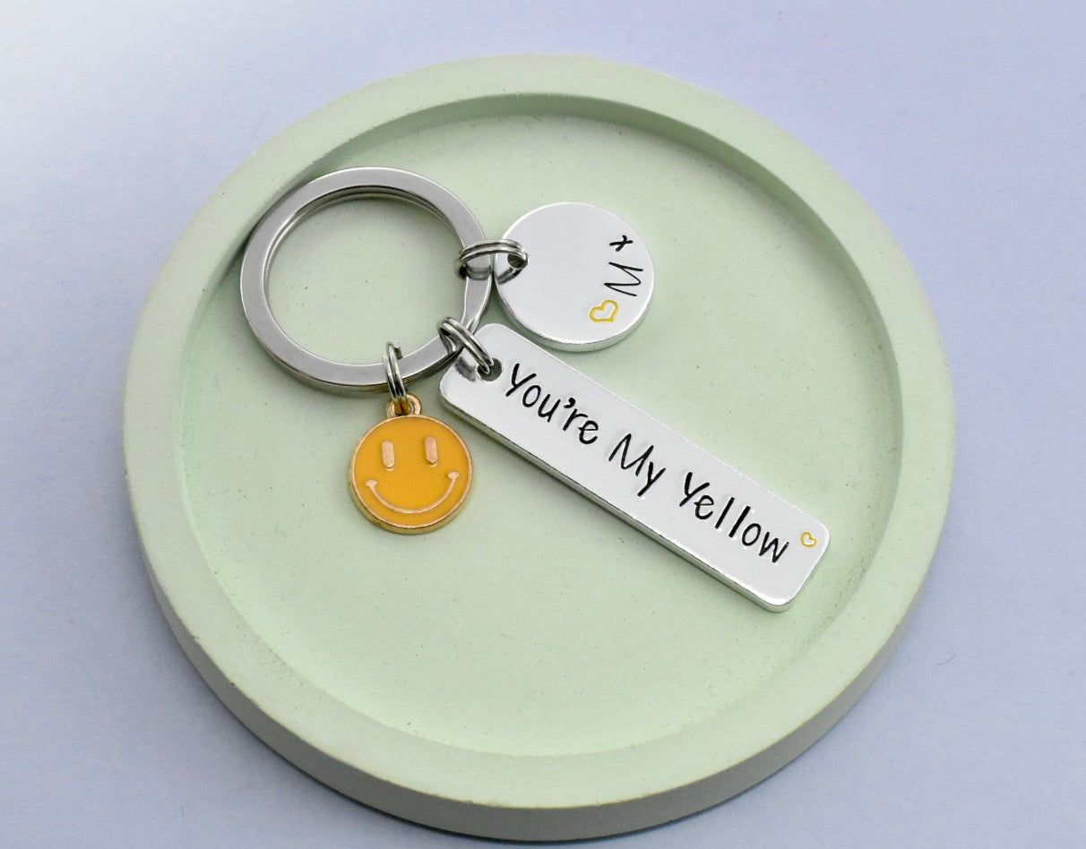 Keychain with 'You're My Yellow' tag and smiley face charm on a green dish