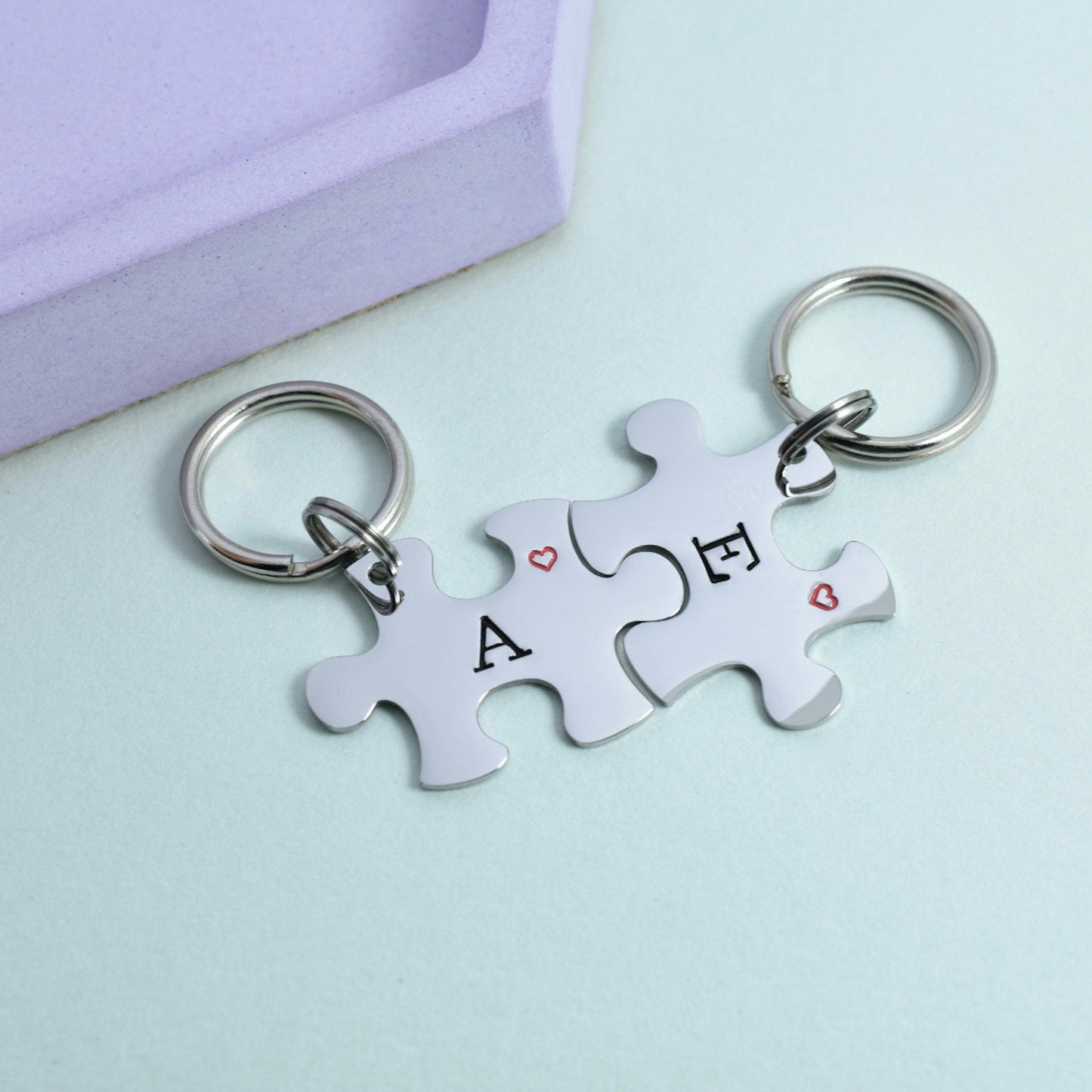 Personalised matching puzzle piece keyrings engraved with initials 'A' and 'F', featuring small heart designs, perfect for couples or best friends