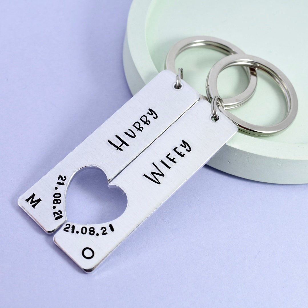 A keyring set with one keychain engraved 'Hubby' and the other 'Wifey', with a heart shape cut out and personalised text below.