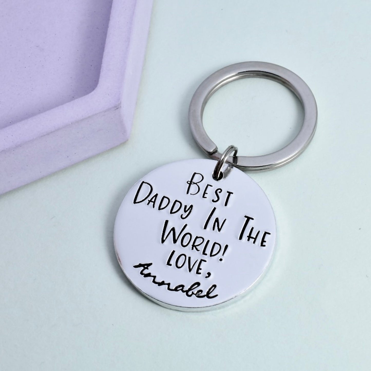 A silver keyring with a large circular pendant, personalised with the text 'Best Daddy In The World - Love, Annabel'.