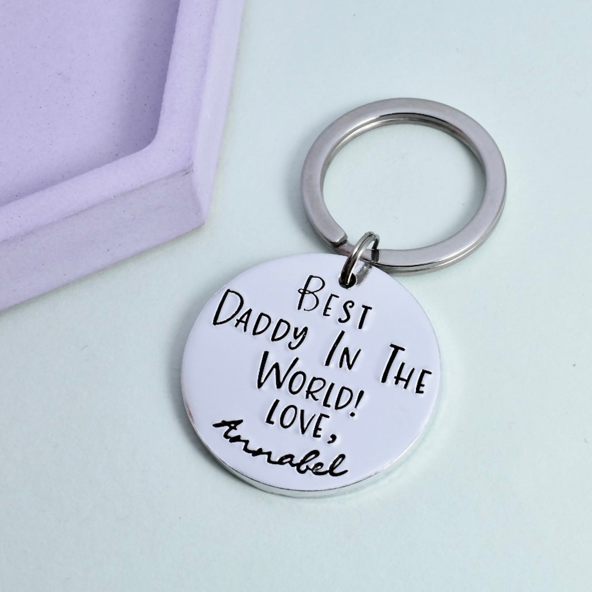 A silver keyring with a large circular pendant, personalised with the text 'Best Daddy In The World - Love, Annabel'.