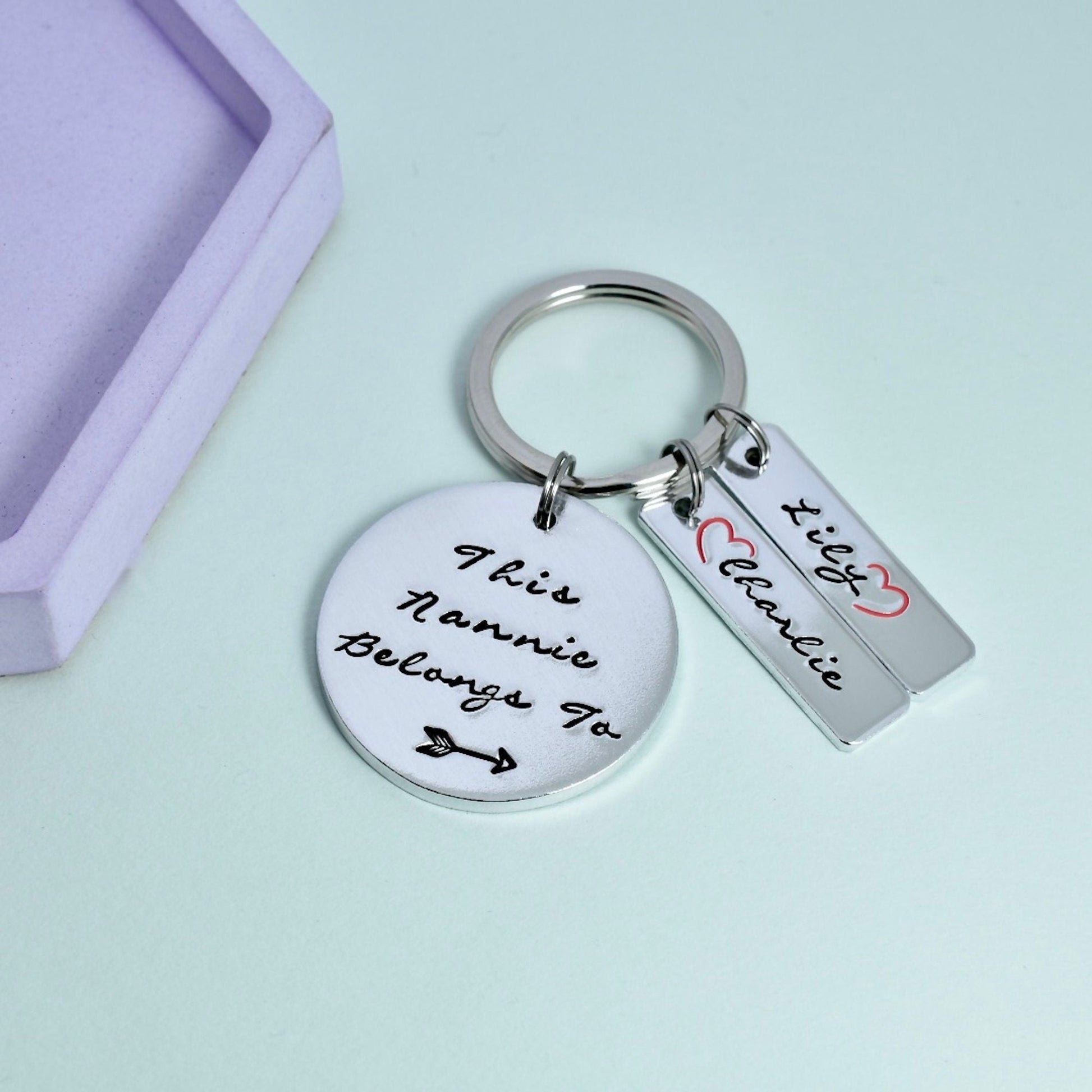 Silver aluminium keyring, persoanlised "this nannie belongs to " on disc, silver rectangle tags are personalised with red open hearts and children's names