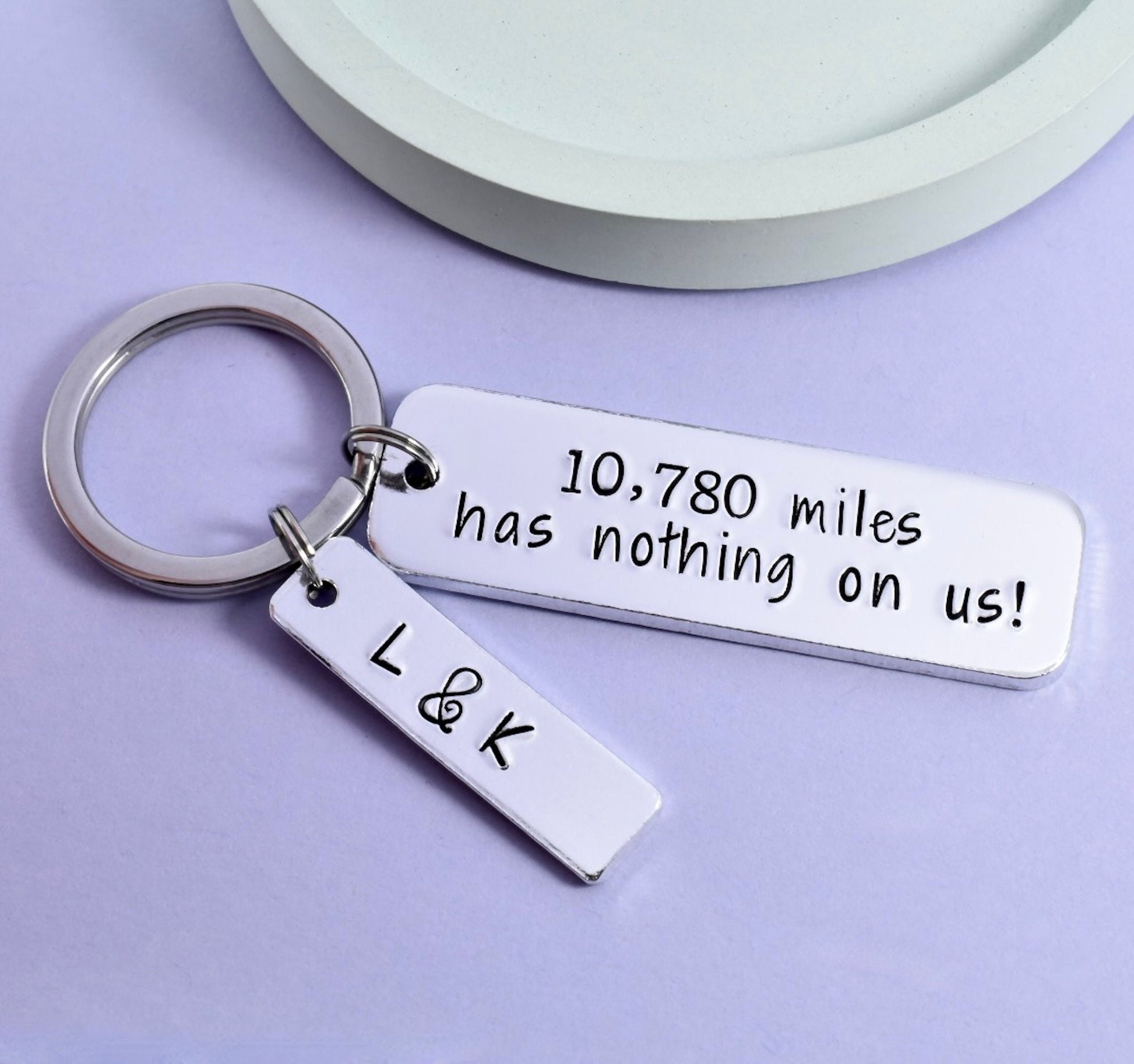 A personalised keyring featuring the text '10,788 miles has nothing on US!' along with some initials 'LK&K'. 