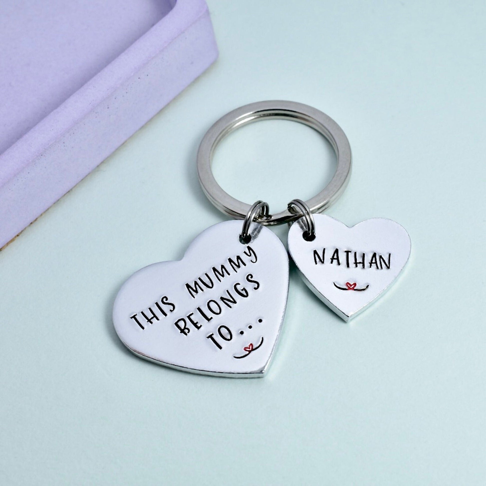 A silver keyring with two heart-shaped charms, one large with the inscription 'This Mummy Belongs To.