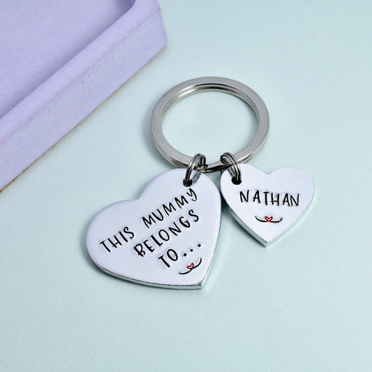 A silver keyring with two heart-shaped charms, one large with the inscription 'This Mummy Belongs To.