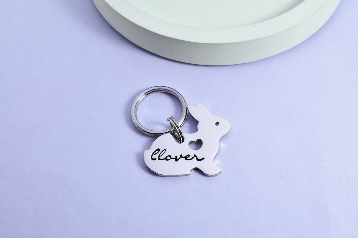 A small stainless steel keyring in the shape of a rabbit, with the name 'clover' inscribed on it