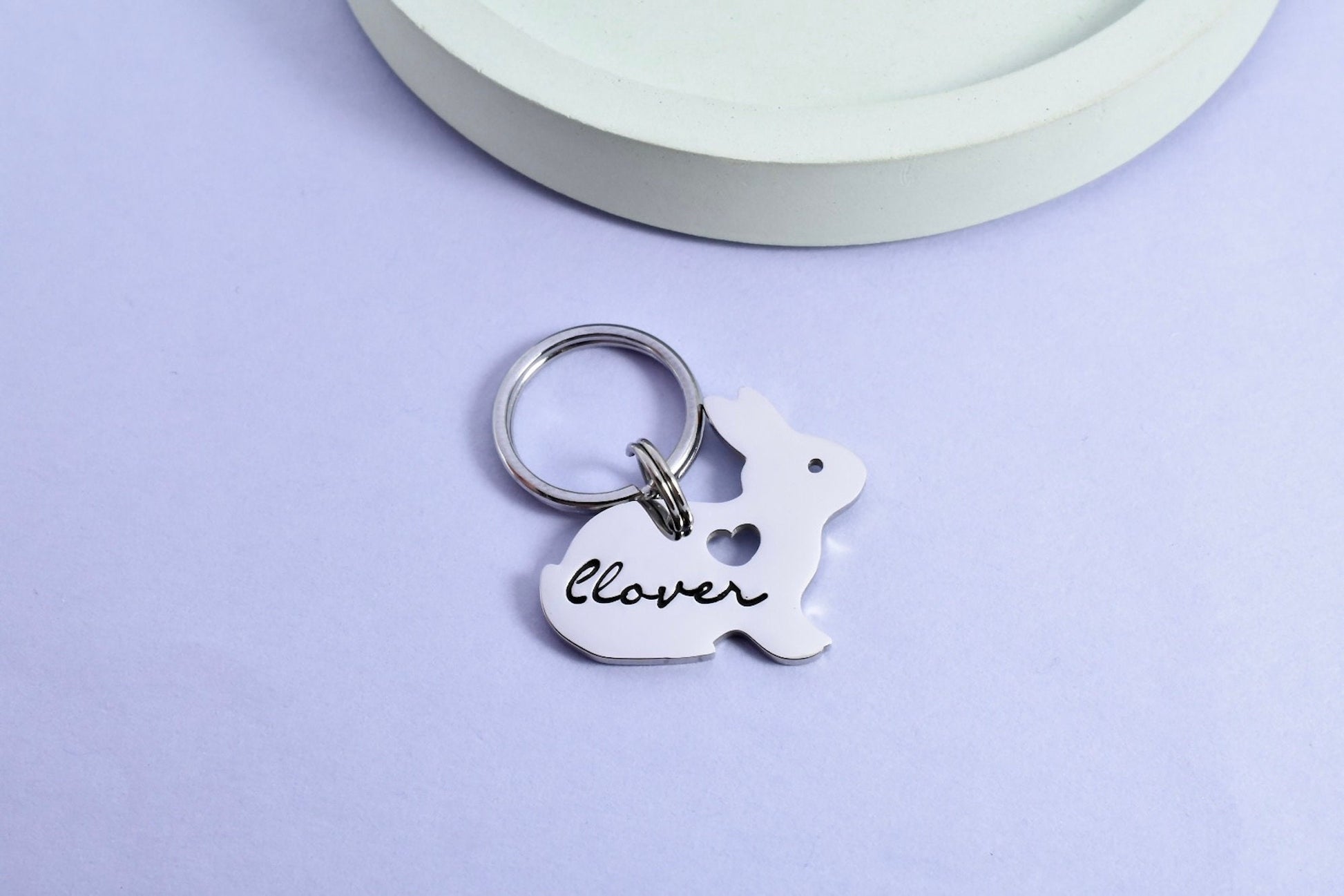 A small stainless steel keyring in the shape of a rabbit, with the name 'clover' inscribed on it