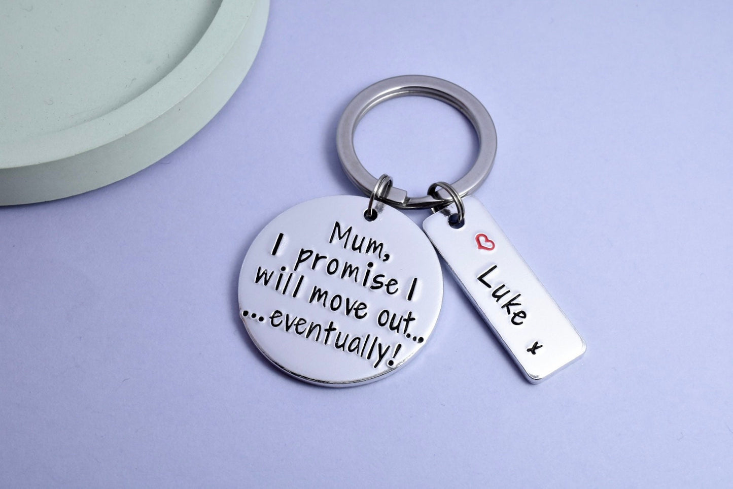 Silver aluminium keyring with name plate tag. disc says "Mum, I promise I will move out...eventually!" rectangle tag is personalised with red heart and name